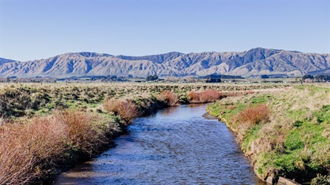 Water runs gently through a stream with the ranges looming in the background.
