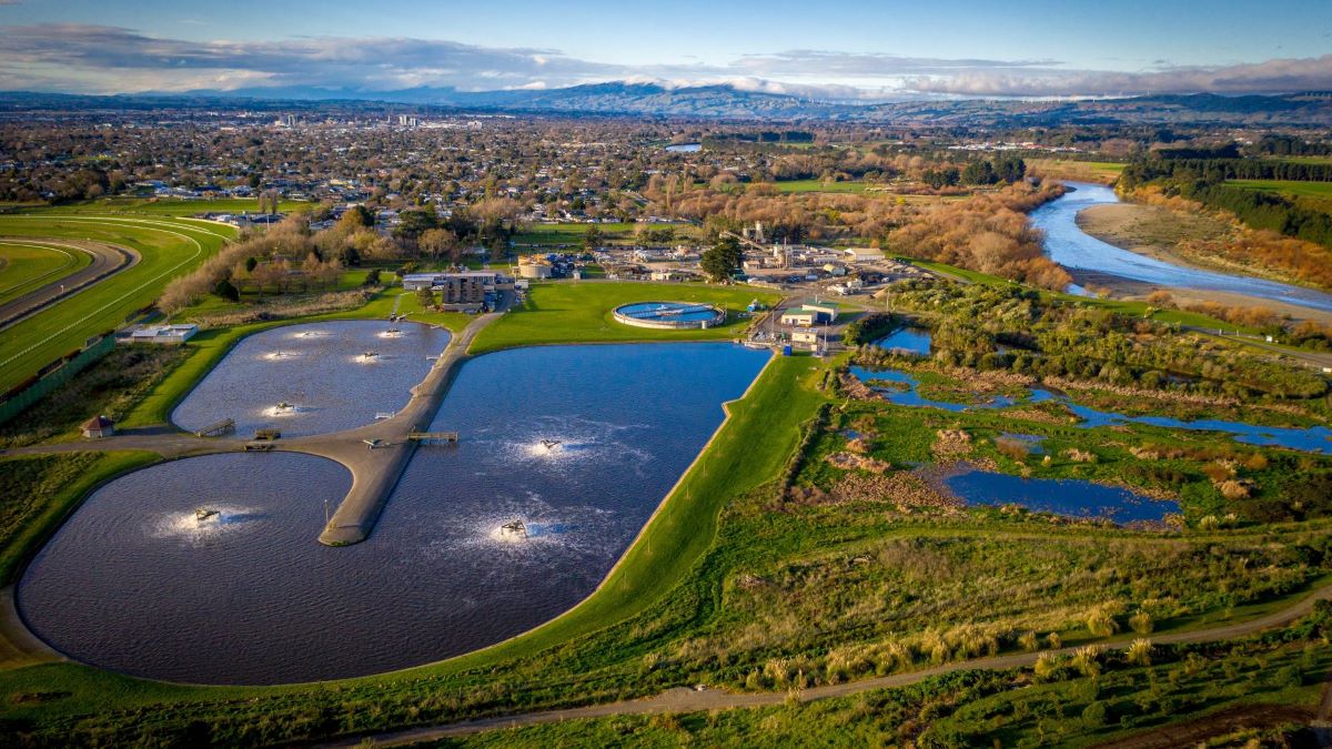 Aerial view of wastewater treatment plant and ponds near the river.